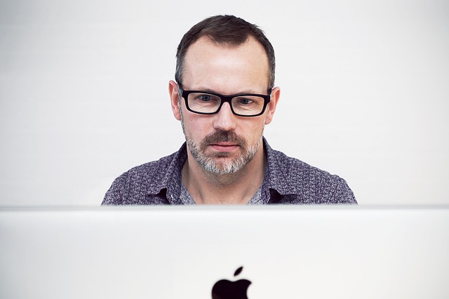 Muž v dioptrických okuliaroch pozerá prekvapene na monitor počítača
